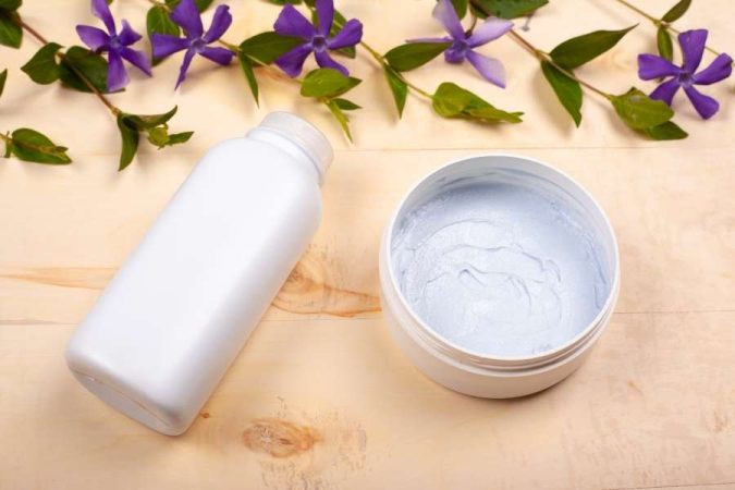Bonne crème solaire en pot avec texture visible et fleurs naturelles en arrière-plan