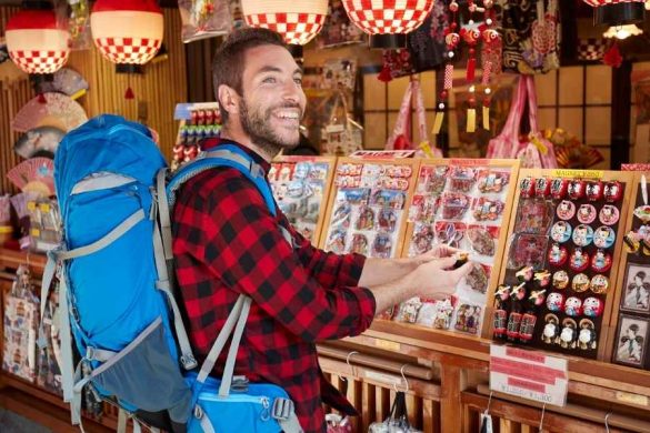 Un homme avec un sac à dos choisit des souvenirs dans une boutique.