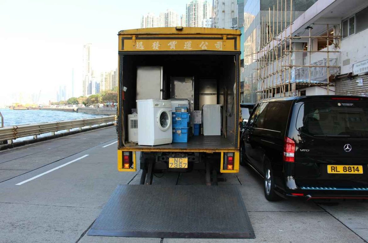 Camion de déménagement jaune ouvert contenant un lave-linge et un réfrigérateur stocké à la verticale pour savoir combien de temps avant déménagement brancher un frigo.